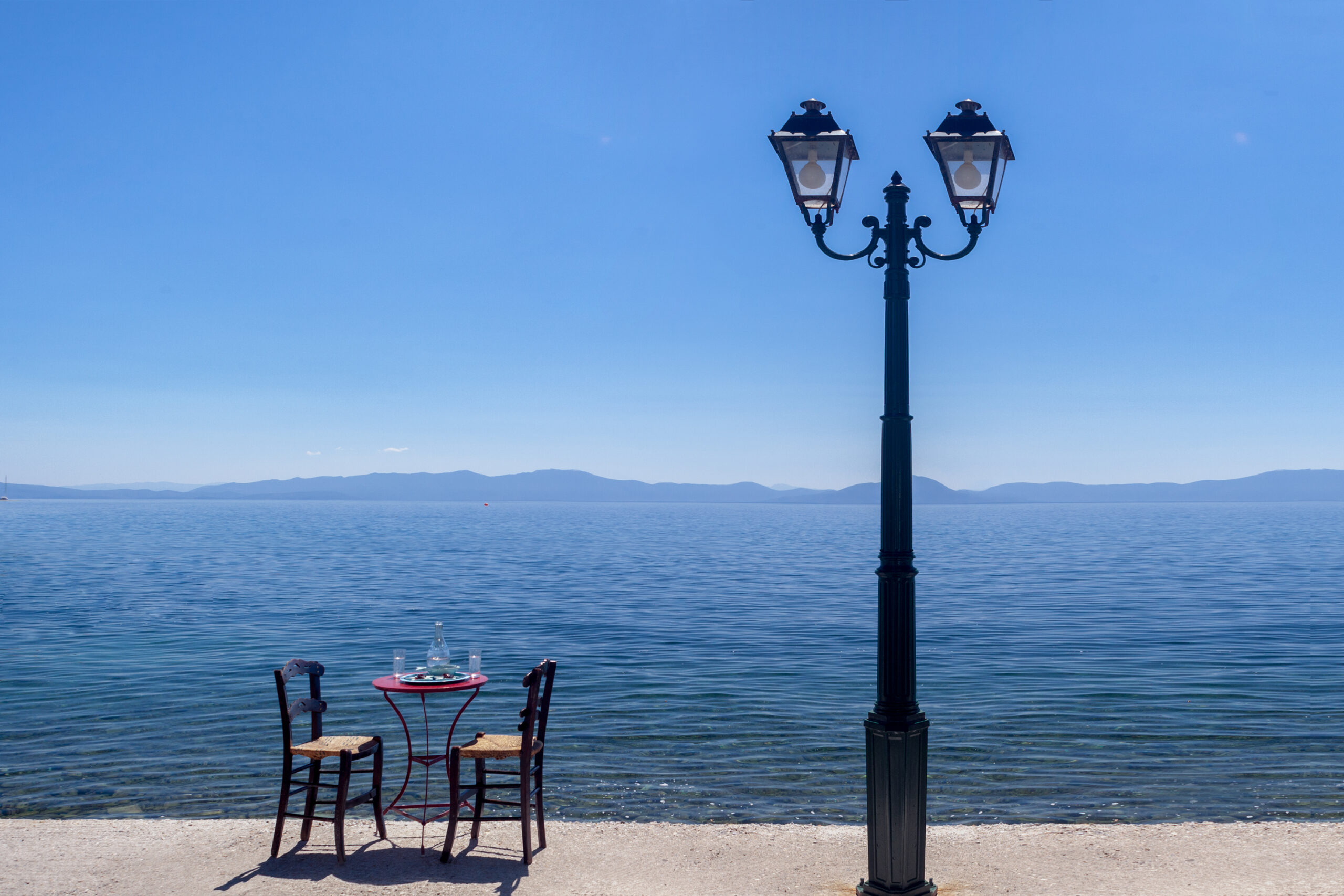 Peaceful seaside setting in Pelion with two chairs, a small table, and a lantern under the summer light.