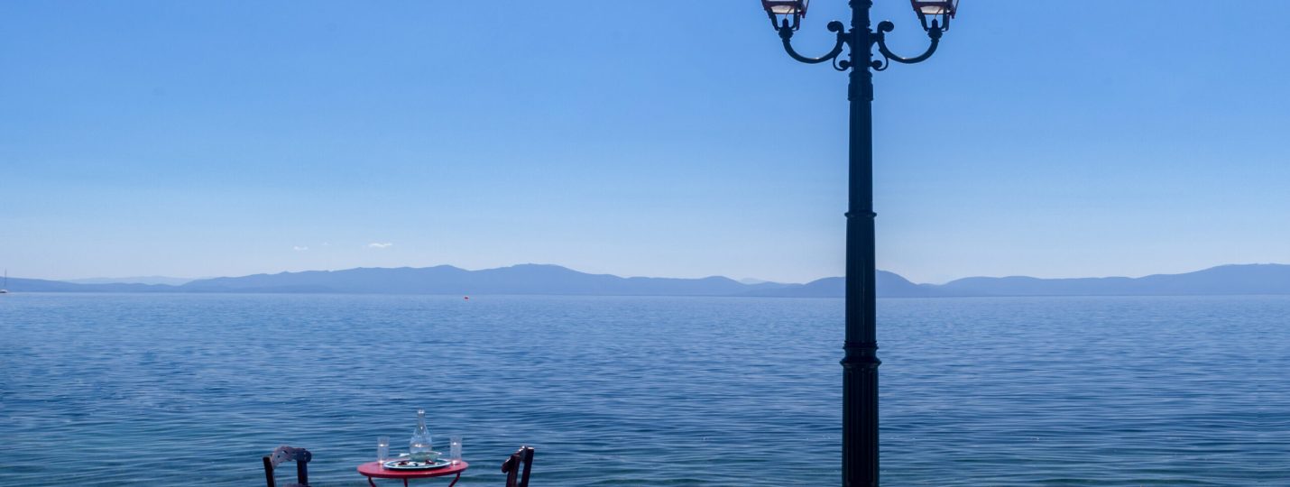 Ήρεμο σκηνικό δίπλα στη θάλασσα στο Πήλιο με δύο καρέκλες, ένα μικρό τραπέζι και φανάρι κάτω από το καλοκαιρινό φως.