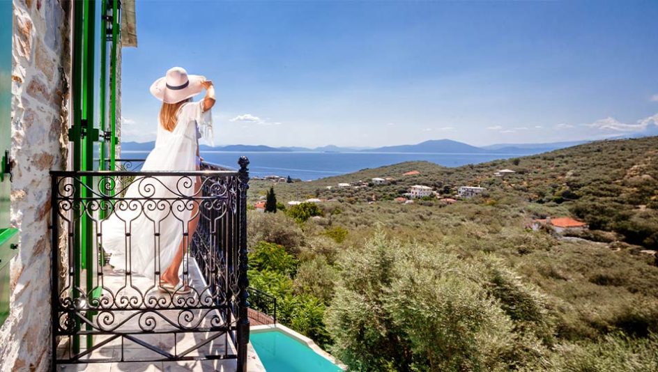Woman enjoying balcony view of Aegean Sea from traditional Pelion villa at Pelion Esties