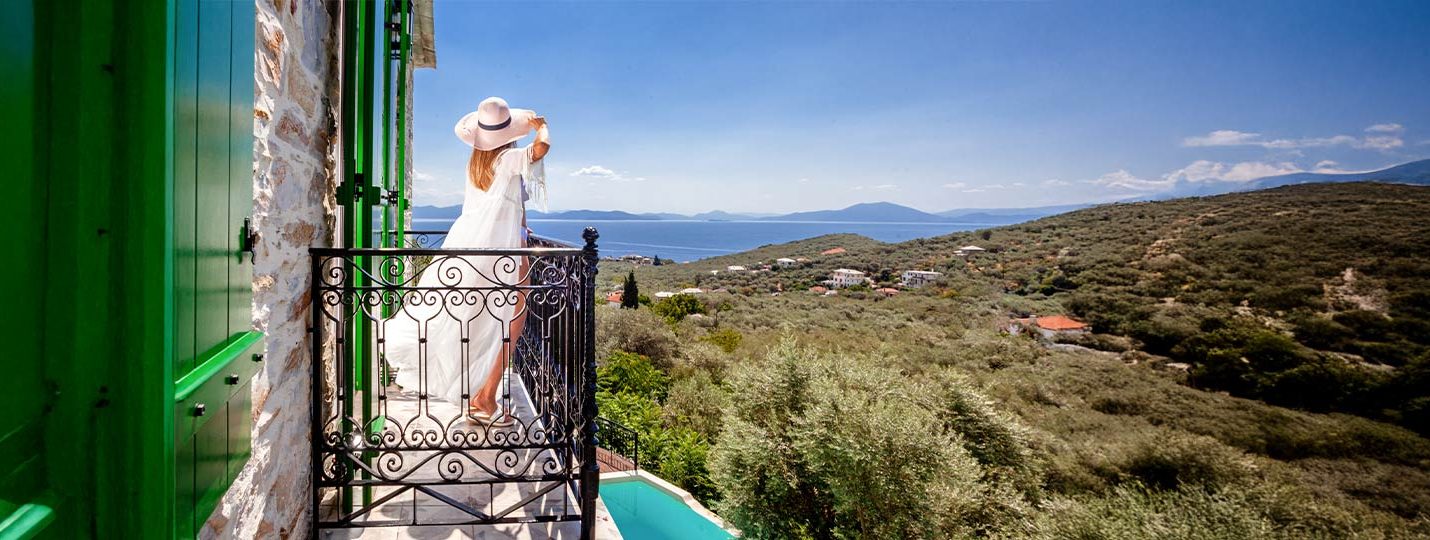 Γυναίκα απολαμβάνει θέα στον Παγασιτικό από μπαλκόνι παραδοσιακής βίλας στο Πήλιο στις Pelion Esties.