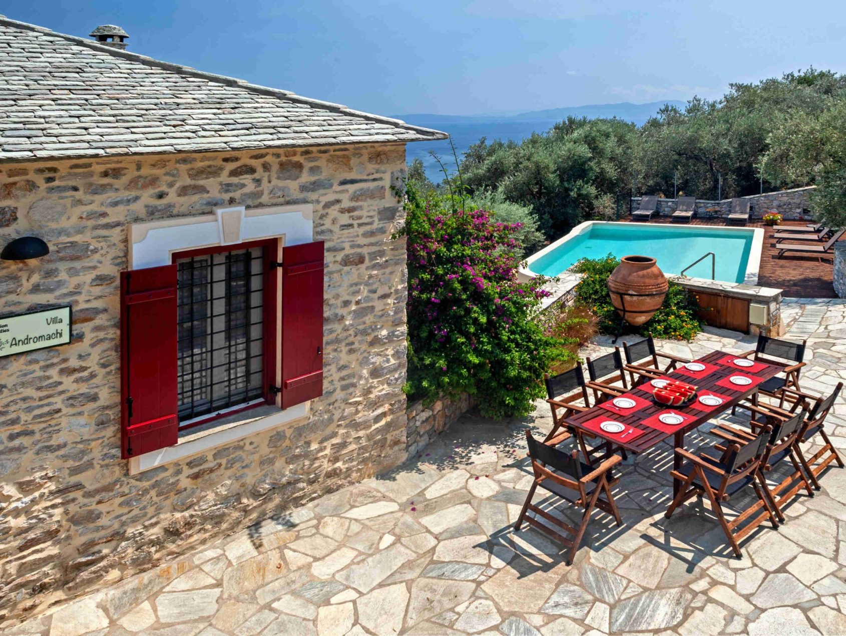 Όμορφη πέτρινη βίλα με εξωτερικό χώρο τραπεζαρίας, ζωντανά λουλούδια και πισίνα.