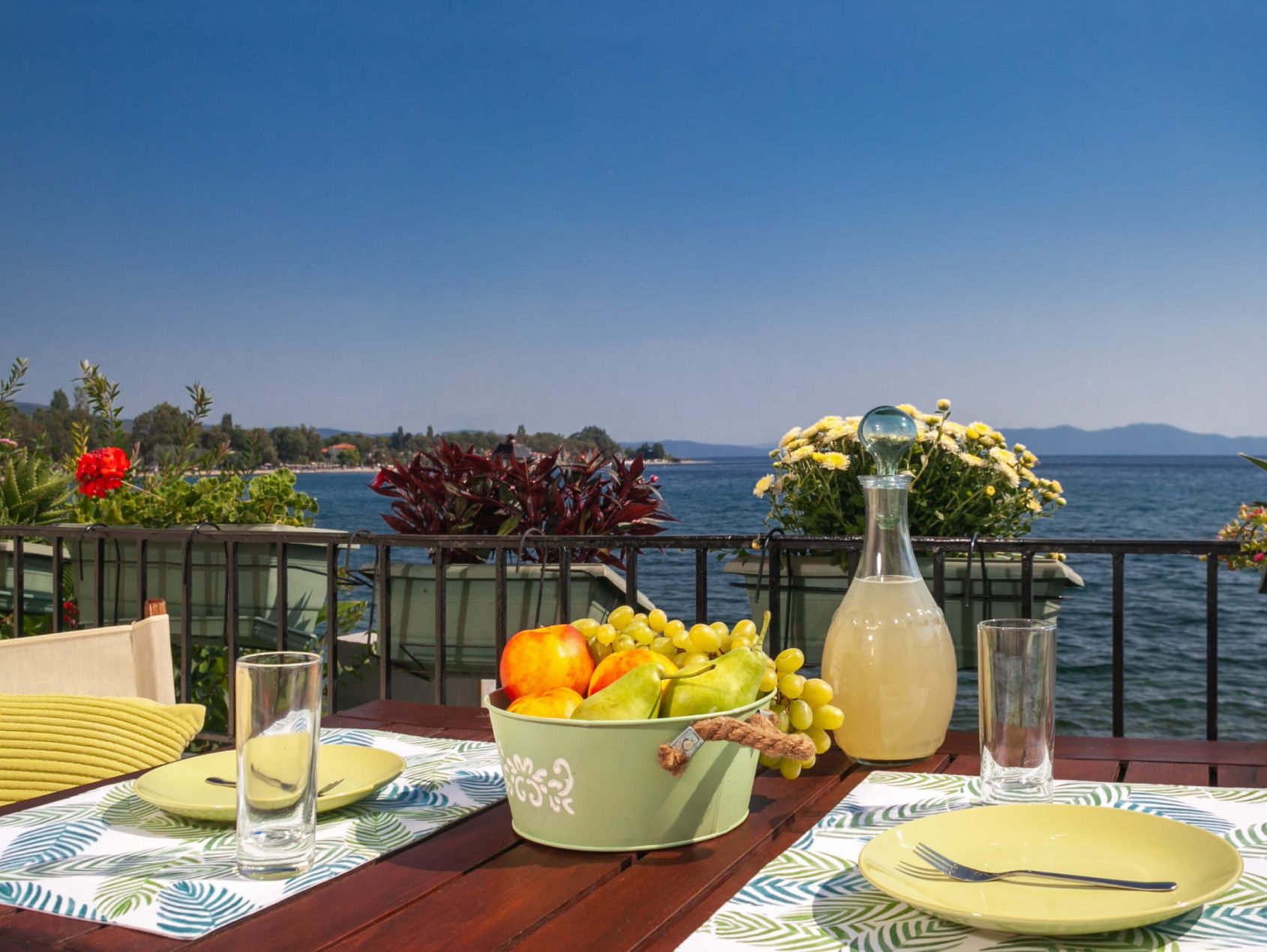 Καλάθι φρούτων και μπουκάλι λεμονάδα σε εξωτερικό τραπέζι με μαγευτική θέα στη θάλασσα, στο Avgi by the Sea, Pelion Villas.