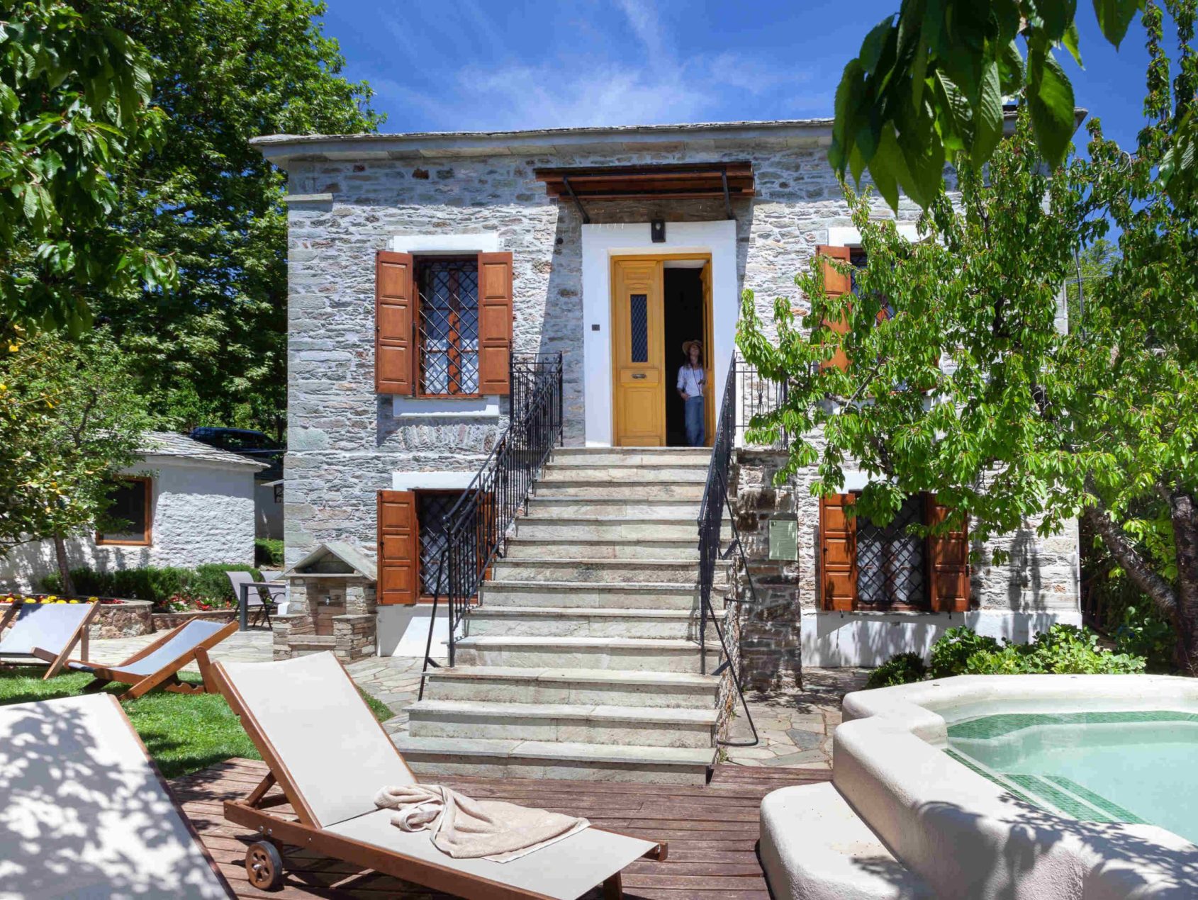 Εξωτερική όψη της Villa Erifili με καταπράσινο κήπο, ξαπλώστρες και τζακούζι από το Pelion-villas.com.