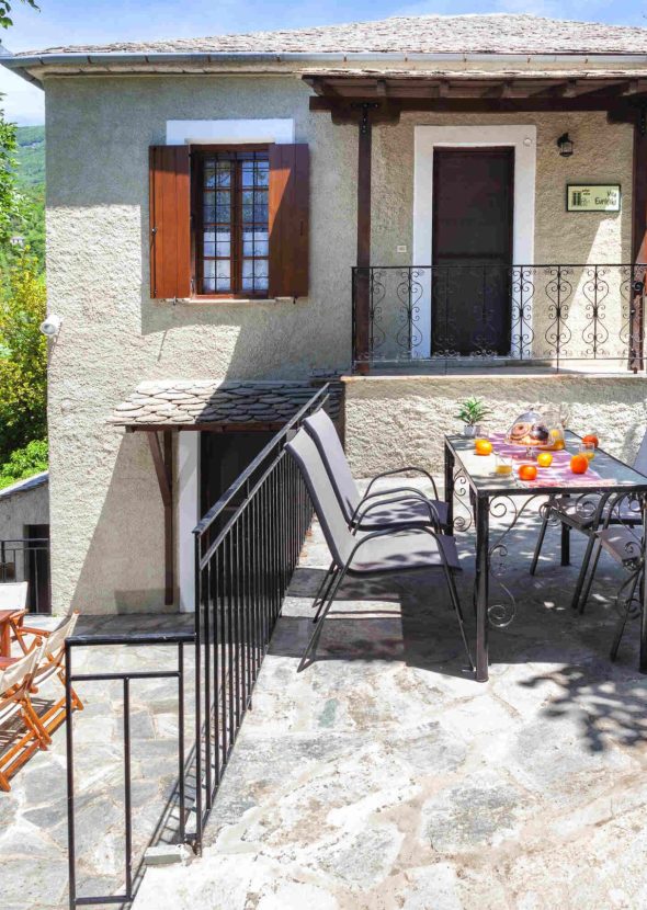 Εξωτερική βεράντα με τραπεζαρία και καθιστικό, περιτριγυρισμένη από πράσινο στη Villa Evridiki, Pelion-villas.com.