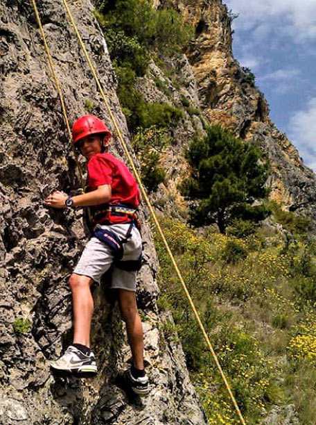 Child rock climbing on the cliffs of Pelion, overlooking the sea, near pelion-villas.com.