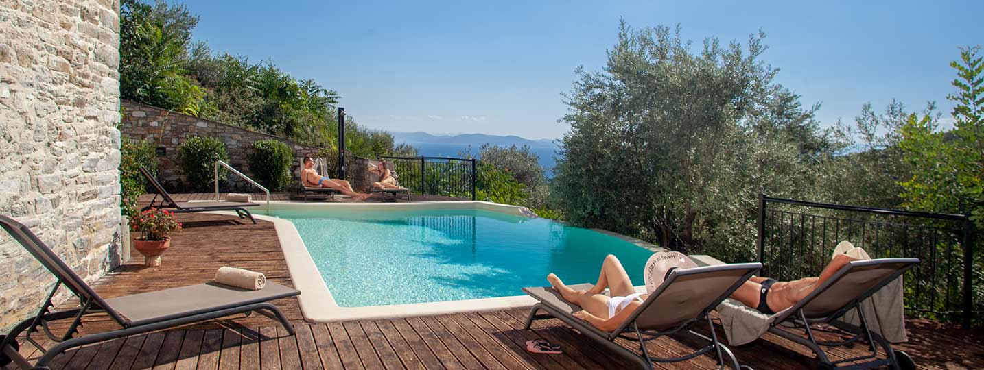 Travelers enjoying a luxury stay with outdoor pool and panoramic landscape at Pelion Esties