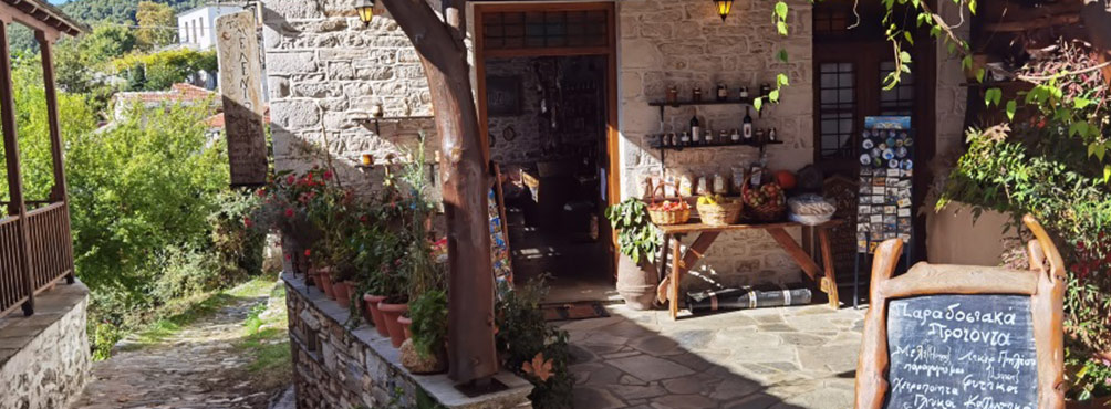 Παραδοσιακό μαγαζί στο Πήλιο με τοπικά προϊόντα όπως μέλι, γλυκά του κουταλιού, βότανα και λικέρ, σε πέτρινο χωριό.