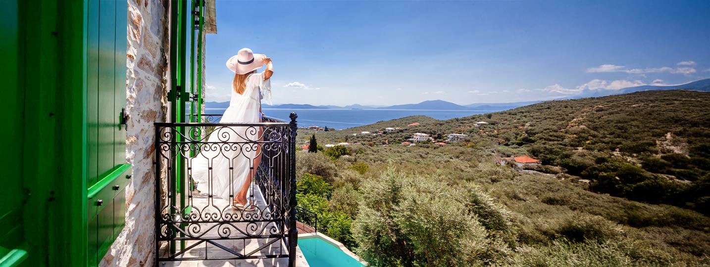 Woman enjoying balcony view of Aegean Sea from traditional Pelion villa at Pelion Esties