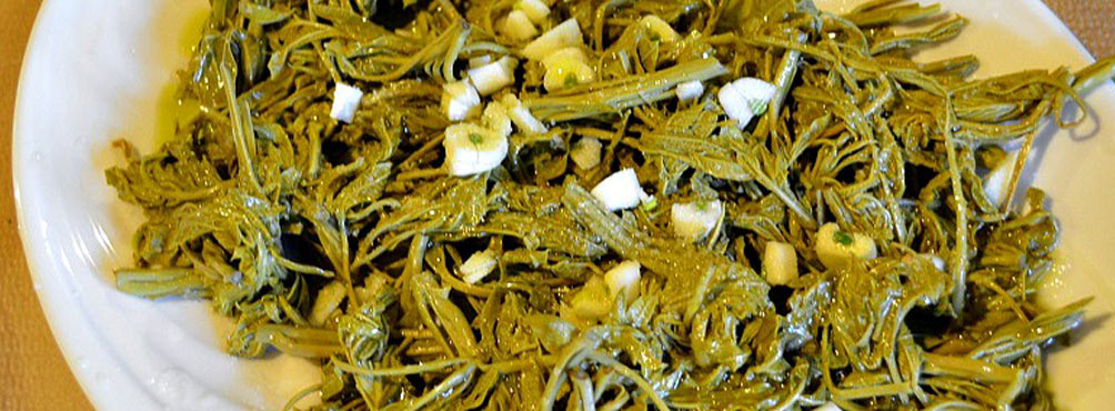 A plate of traditional Greek wild greens (horta) with olive oil and garlic, served as a side dish in a Pelion tavern.