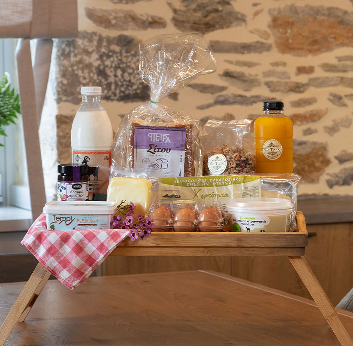 Breakfast tray with fresh bread, Greek yogurt, eggs, cheese, butter, and orange juice, highlighting local dairy products by Pelion-villas.com."