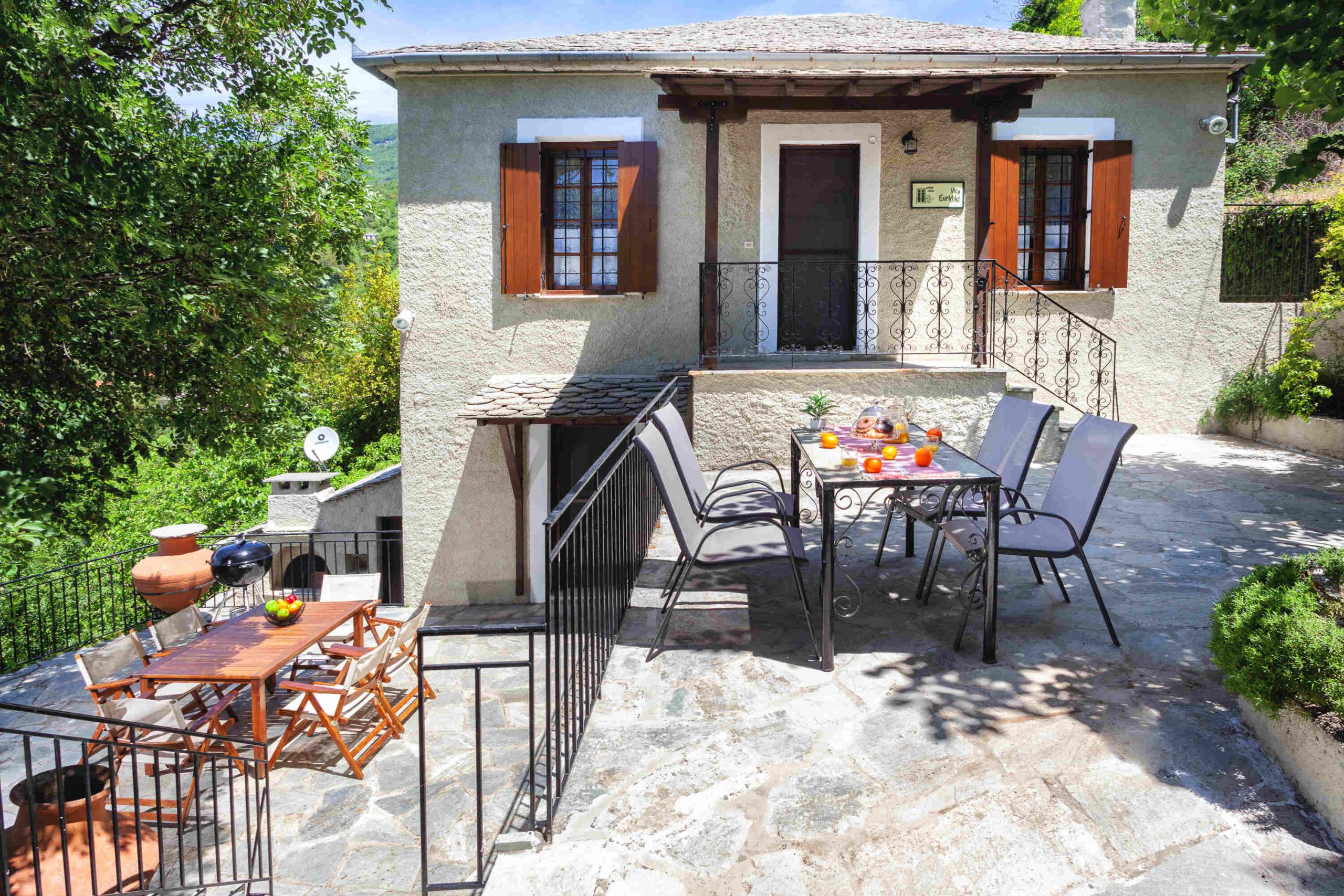 Outdoor terrace with dining and seating area, surrounded by greenery at Villa Evridiki, Pelion-villas.com.